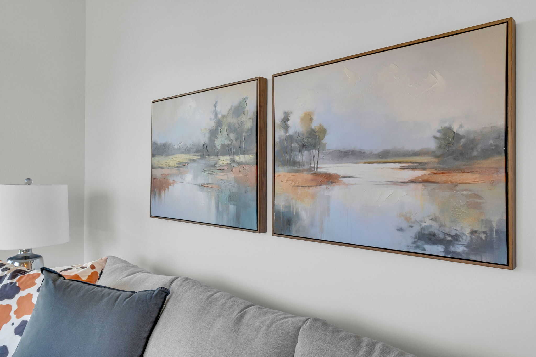 two landscape pictures above white couch against white walls. Stage and Style by Leigh Edmonton