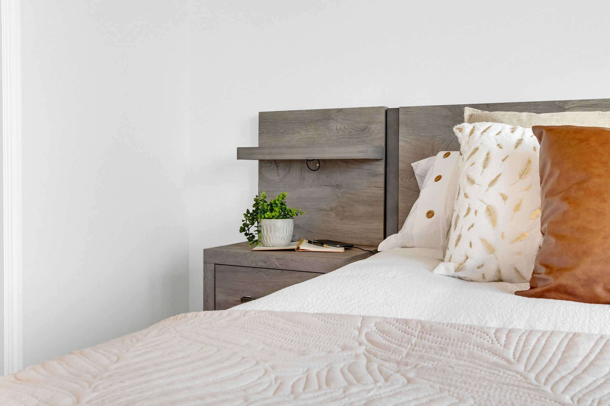 bedroom with white walls, darker furniture, white and cream bedding